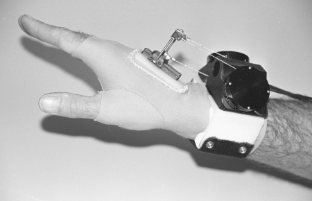 Figure A1 - The wrist goniometer mounted on the right hand, illustrating the hand component and the forearm components. The forearm component includes the wrist band and the housing for the three SpaceAge Control position transducers.  The hand component includes the elastic glove and hardware for attachment of the displacement cable ends. <em>Photo credit: Liberty Mutual Research Institute for Safety.